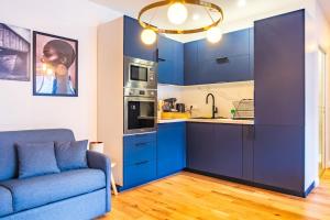 a kitchen with blue cabinets and a blue couch at Studio Élégant - Proche Paris & La Défense in Rueil-Malmaison