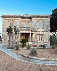 a large stone house with palm trees in front of it at Kikka B&B in Tarxien