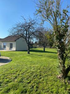 a grassy yard with trees and a house at Gîte la pause en baie in Pendé