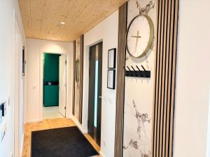 a hallway with a clock on the wall and a black rug at Chalet du calme Gersthofen in Gersthofen