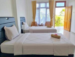 two beds in a room with a window at Arirang Sea View Homestay in Senggigi