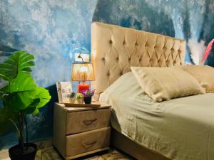 a bedroom with a bed and a night stand with a lamp at Riad Sor in Essaouira