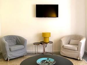 two chairs and a table in a room with a tv at Casa Obìa in Cagliari