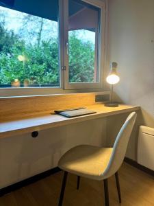 a desk with a chair and a window and a lamp at Campanile NATURE -Haguenau in Haguenau