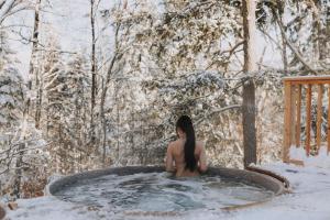 a woman sitting in a hot tub in the snow at Private Nordic Spa Retreat - Mont-Tremblant in Lac-Superieur