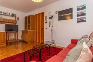 a living room with a red couch and a table at Condominio Meraviglia in Selva di Cadore