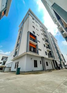 a tall white building with an orange window at LetMax Homes in Ikeja
