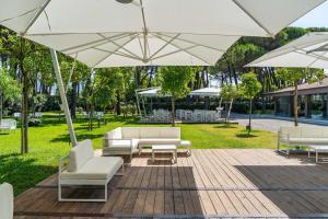 a patio with white chairs and tables and umbrellas at Otium Mare Felix in Stazione di Paestum