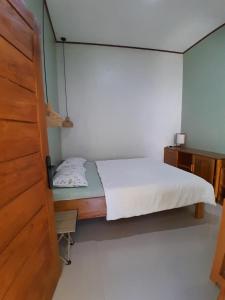 a small bedroom with a bed and a wooden door at anik homestay & dormy Batukaras in Batukaras