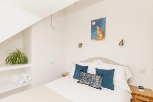 a white bedroom with a bed with blue pillows at Tokenhill Cottage in Dorchester