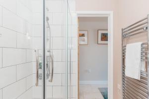 a glass shower in a bathroom with white tiles at Tokenhill Cottage in Dorchester