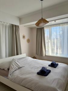 two towels on a bed in a bedroom with a window at Sea You Soon in De Haan