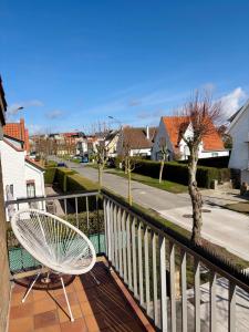 a white chair sitting on a balcony next to a street at Sea You Soon in De Haan