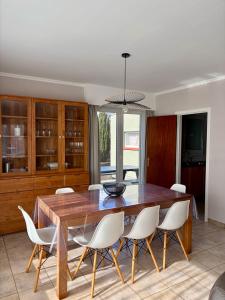 a dining room with a wooden table and white chairs at Sea You Soon in De Haan