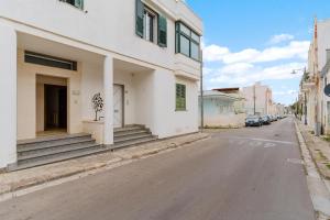 a white building with a tree on the side of a street at Lamendolara B&B in Specchia