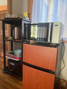 a microwave oven on top of a wooden cabinet at 杜の宿 らくう庵 山鹿 in Yamaga
