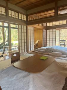 a bedroom with a large bed in a room with windows at 杜の宿 らくう庵 山鹿 in Yamaga