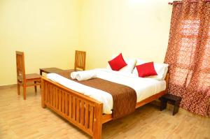 a bedroom with a large bed with red pillows at Redfox Villa - Kodaikanal in Kodaikānāl