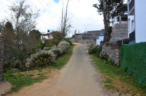a dirt road next to a fence and a building at Redfox Villa - Kodaikanal in Kodaikānāl