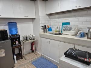a small kitchen with white cabinets and a sink at Door207 Homestay in Baguio