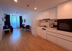 a kitchen with white cabinets and a living room at Sun Set Apartments in Batumi