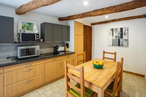 a kitchen with a wooden table with chairs and a microwave at Maison de l'Orb in Cessenon