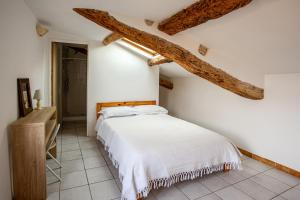 a bedroom with a white bed and wooden beams at Maison de l'Orb in Cessenon