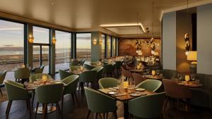a restaurant with tables and chairs and windows at Seamill Hydro Hotel in Seamill