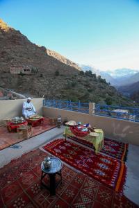a man sitting on a balcony with a view of a mountain at Adrar view lodge in Imlil