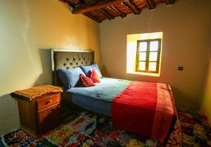 a bedroom with a bed with red pillows and a window at Adrar view lodge in Imlil +13 photos