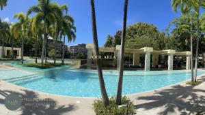 a swimming pool at a resort with palm trees at Nade Suites - Pico De Loro MIB 601 in Nasugbu