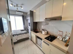 a small kitchen with white cabinets and a bed at Four Living Sky House BSD in Samporo