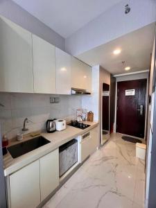 a kitchen with white cabinets and a sink at Four Living Sky House BSD in Samporo