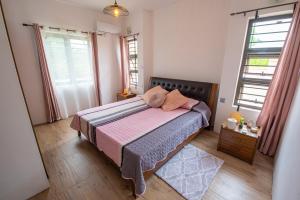 a bedroom with a bed with pink sheets and two windows at Villa Le Mahé, Mahébourg in Mahébourg +12 photos