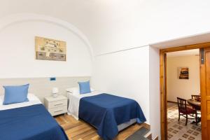a bedroom with two beds with blue sheets and a table at Il Giardino dei Gigli in Meta