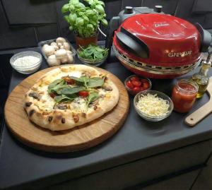 a pizza on a cutting board on a counter with ingredients at Biała Mewa in Huta