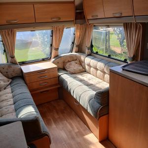 a couch in the back of an rv with two windows at CaraCaux in Le Torp-Mesnil