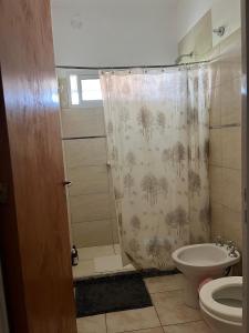 a bathroom with a shower curtain and a toilet at Casa 2 Habitaciones in Las Varillas +3 photos