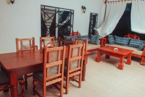 a dining room with a table and chairs and a couch at Villa Franet in Watamu