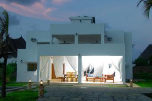 a white house with two chairs and a table at Villa Franet in Watamu