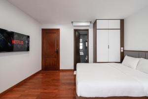 a bedroom with a white bed and a wooden floor at Luxe Paradise Suites - No34 Alley 260 Đội Cấn in Hanoi