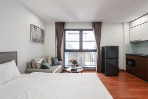 a bedroom with a large white bed and a kitchen at Luxe Paradise Suites - No34 Alley 260 Đội Cấn in Hanoi
