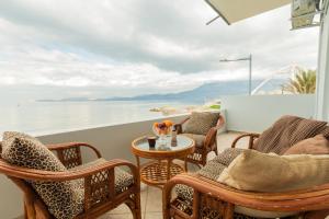 ein Balkon mit Stühlen und einem Tisch mit Blick auf das Wasser in der Unterkunft On The Waves Suites in Korinthos