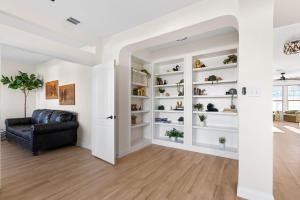 a living room with a black leather couch and white shelves at Large Groups' Luxury House - Pool - Sleep 22 in Round Rock