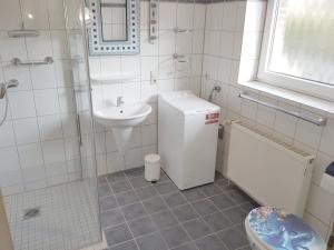 a white bathroom with a sink and a toilet at Ferienhaus Ditzum am Sielblick in Ditzum