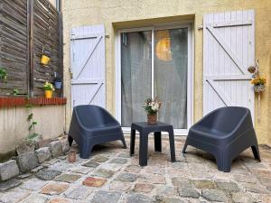 two chairs and a table in front of a door at La Courette des Rois - Hyper centre & Chateau in Dourdan