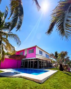 a pink building with a swimming pool and palm trees at Venecia Yatch Club in San Luis La Herradura