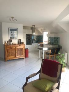 a living room with a chair and a kitchen at Armorique résidence in Malestroit
