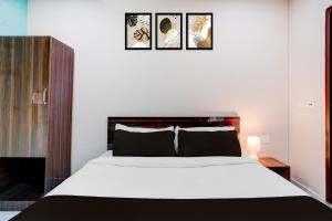 a bedroom with a bed and three pictures on the wall at Hotel O The Pride Inn Basistha Road in Khānāpāra