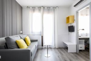 een woonkamer met een grijze bank en gele kussens bij Residencia Universitaria Barcelona Diagonal in Barcelona